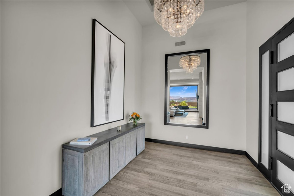 Corridor featuring a notable chandelier and light hardwood / wood-style floors