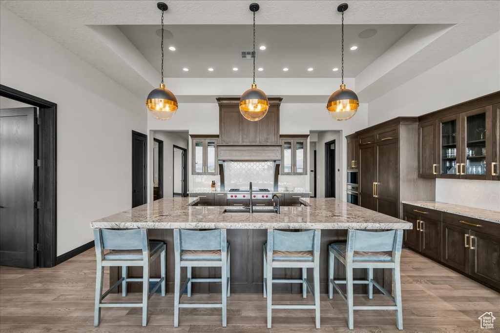 Kitchen with decorative light fixtures, a large island, and a raised ceiling