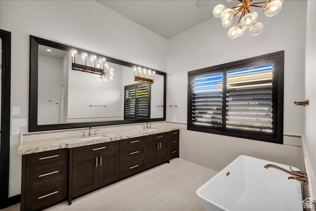 Bathroom with vanity, a chandelier, and a bathing tub