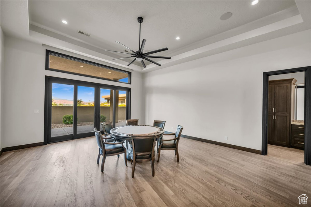 Dining area featuring light wood-type flooring and a tray ceiling