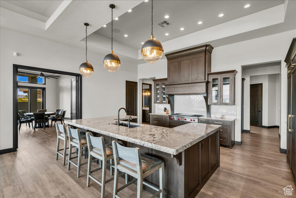 Kitchen featuring light stone countertops, decorative light fixtures, light hardwood / wood-style floors, sink, and a large island