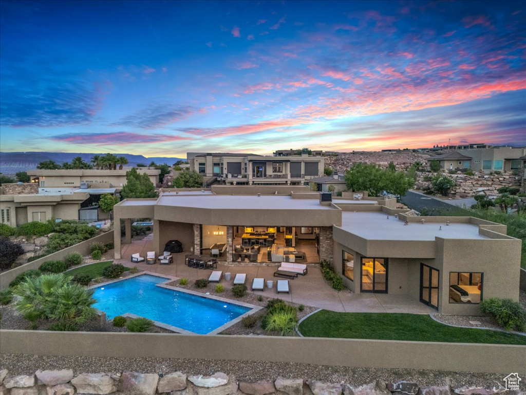 Back house at dusk featuring an outdoor bar, an outdoor living space, and a patio area