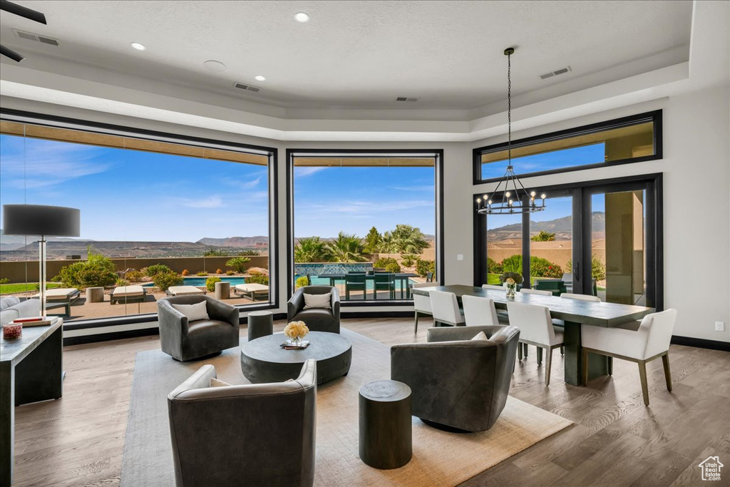 Living room featuring a raised ceiling, a mountain view, a chandelier, and hardwood / wood-style flooring