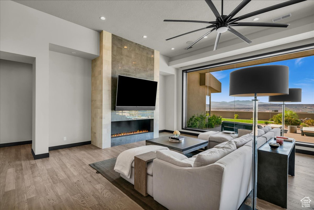 Living room with light wood-type flooring, ceiling fan, and a fireplace