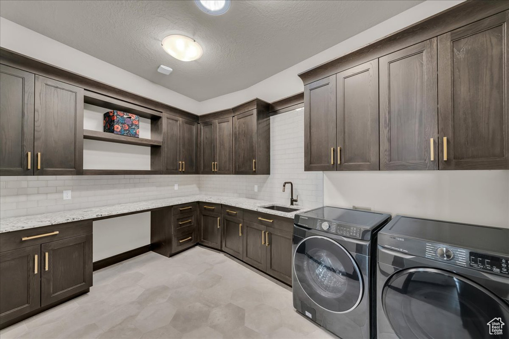 Laundry area featuring a textured ceiling, sink, cabinets, and separate washer and dryer