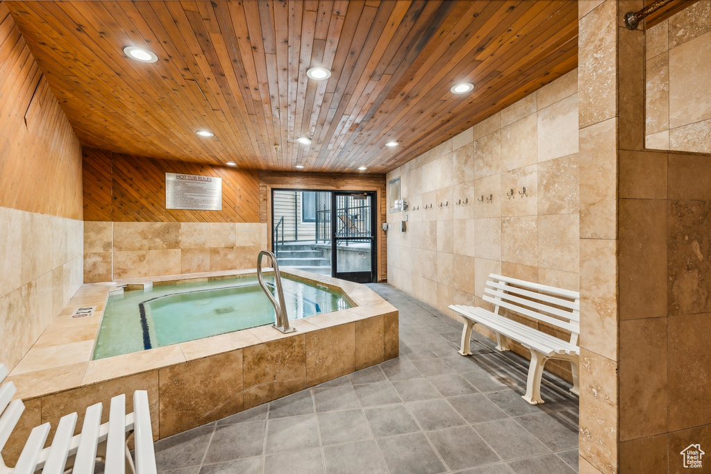 Bathroom with wooden ceiling, tile walls, and tile patterned floors