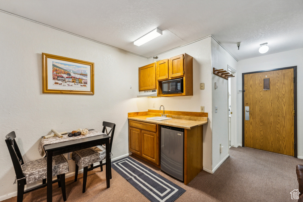 Kitchen featuring dark colored carpet, a textured ceiling, black microwave, and sink