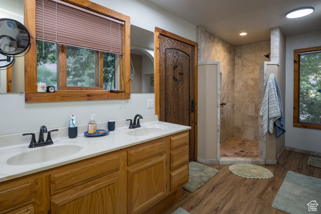 Bathroom featuring a sink, double vanity, walk in shower, and wood finished floors