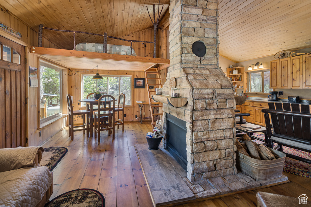 Interior space with a stone fireplace, wood walls, hardwood / wood-style floors, and wooden ceiling