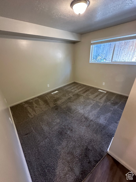 Carpeted empty room featuring a textured ceiling