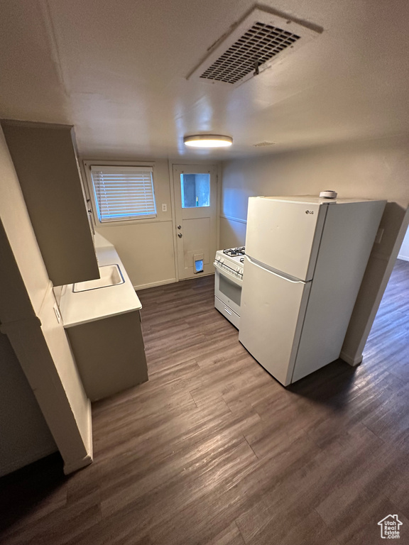 Kitchen featuring hardwood / wood-style flooring, sink, and white appliances