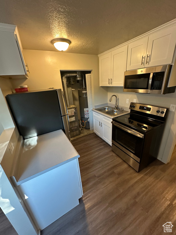 Kitchen with sink, dark wood-type flooring, a textured ceiling, white cabinetry, and stainless steel appliances