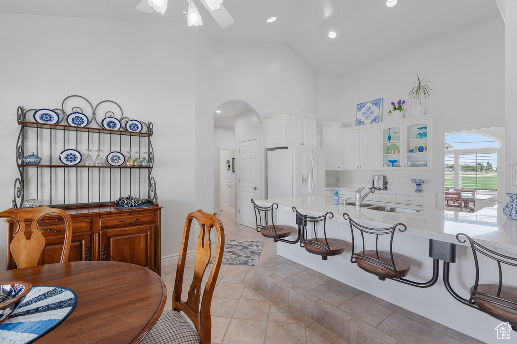 Tiled dining room featuring high vaulted ceiling, sink, and ceiling fan