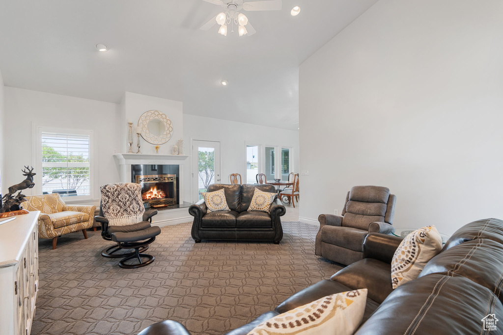 Carpeted living room with lofted ceiling, ceiling fan, and plenty of natural light