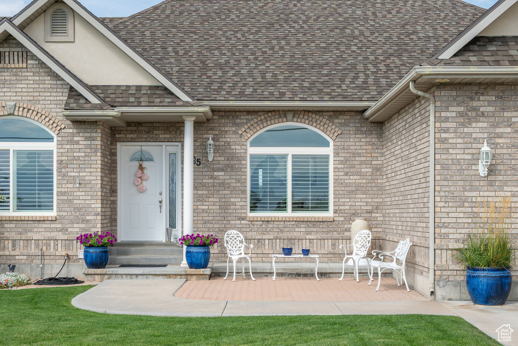 View of exterior entry with a yard and a patio area