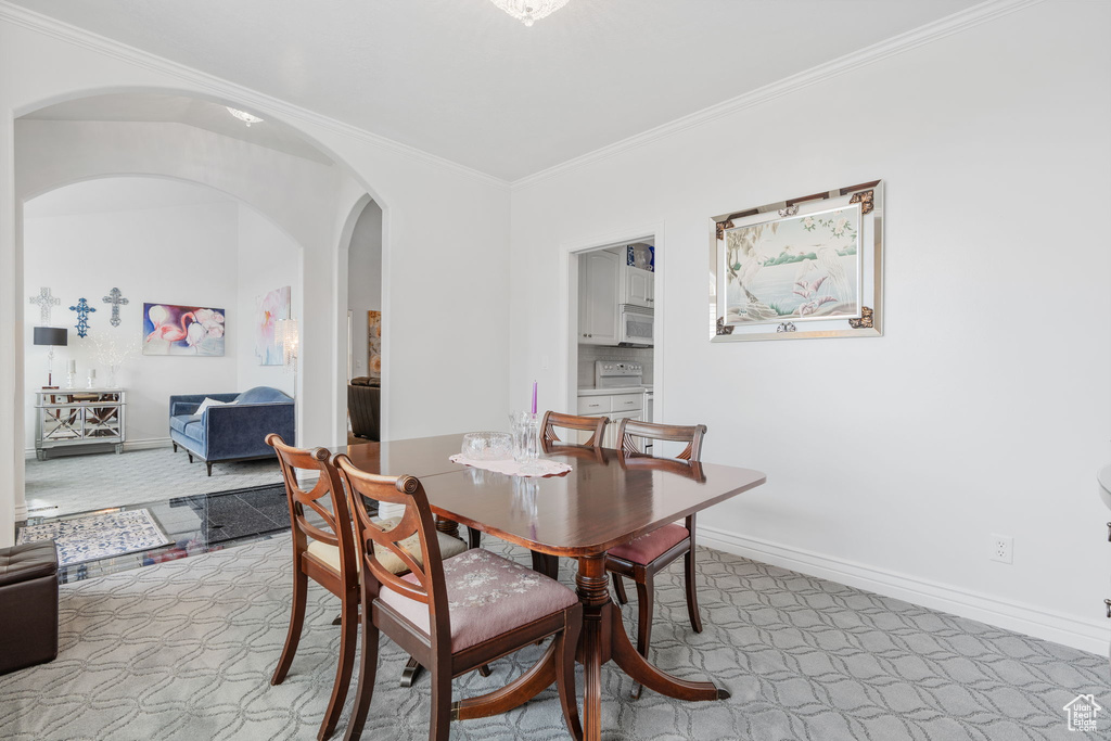 Dining area with crown molding and light colored carpet