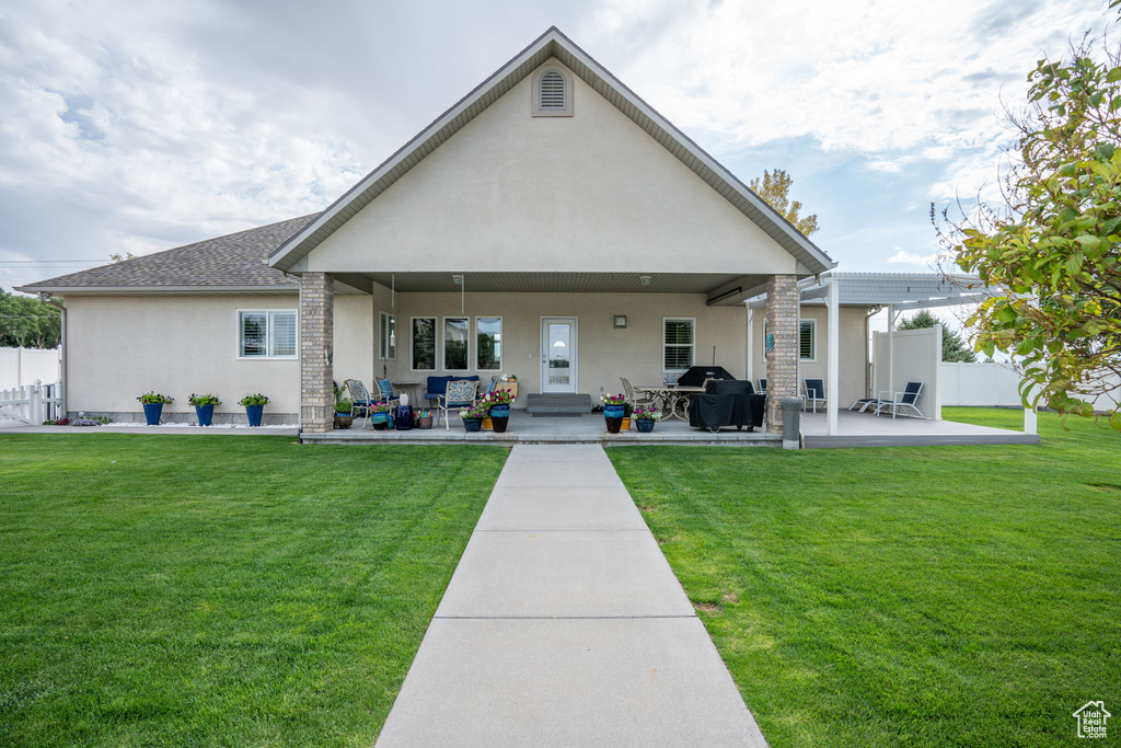 Rear view of property with a lawn and a patio