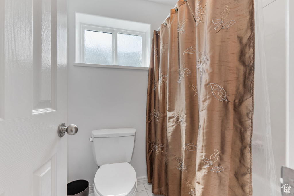 Bathroom featuring toilet, curtained shower, and tile patterned floors