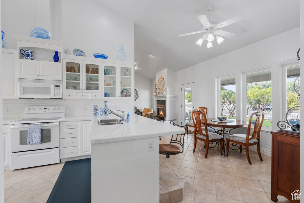 Kitchen with ceiling fan, white appliances, white cabinetry, and light tile patterned flooring