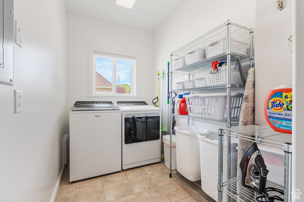 Laundry area with independent washer and dryer and light tile patterned flooring