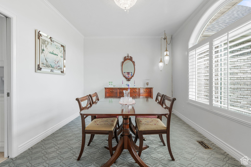 Dining space with a wealth of natural light, crown molding, and carpet