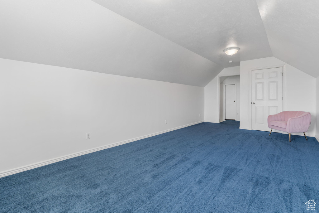 Bonus room featuring vaulted ceiling and dark colored carpet