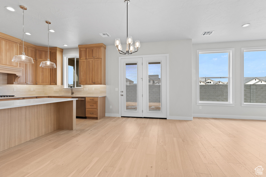 Kitchen with light wood finished floors, decorative backsplash, light countertops, gas stovetop, and stainless steel dishwasher