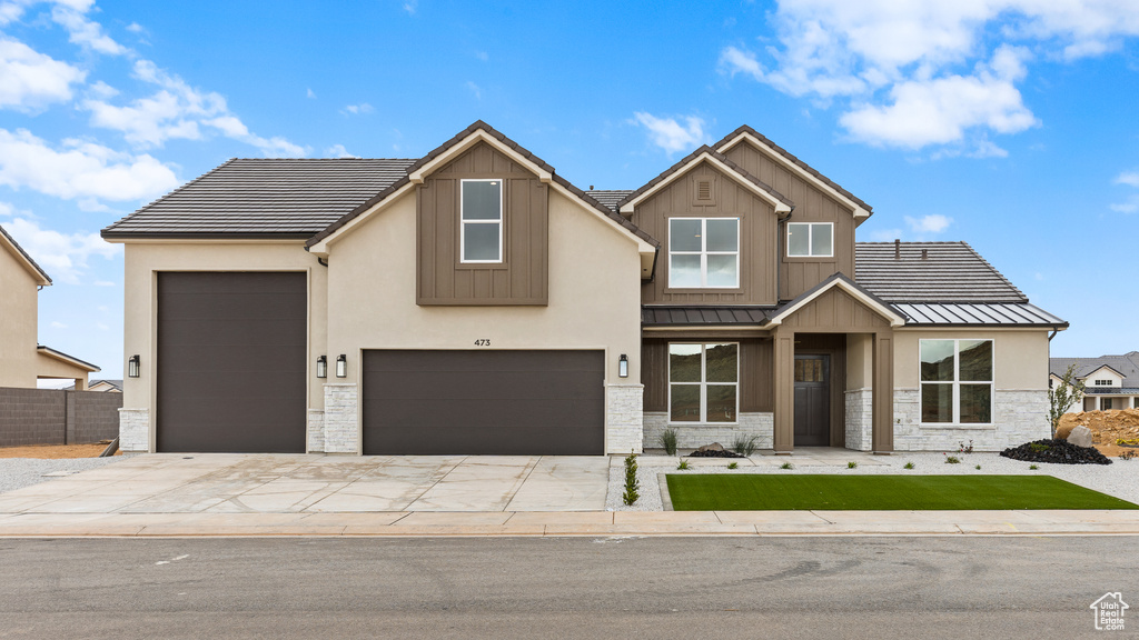 View of front of home with metal roof, concrete driveway, a standing seam roof, and fence