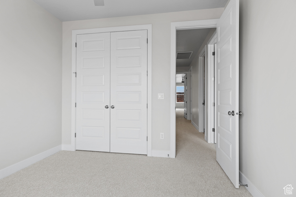 Unfurnished bedroom with light colored carpet, a closet, visible vents, and baseboards