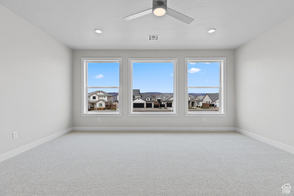 Unfurnished room with baseboards, visible vents, ceiling fan, and light colored carpet