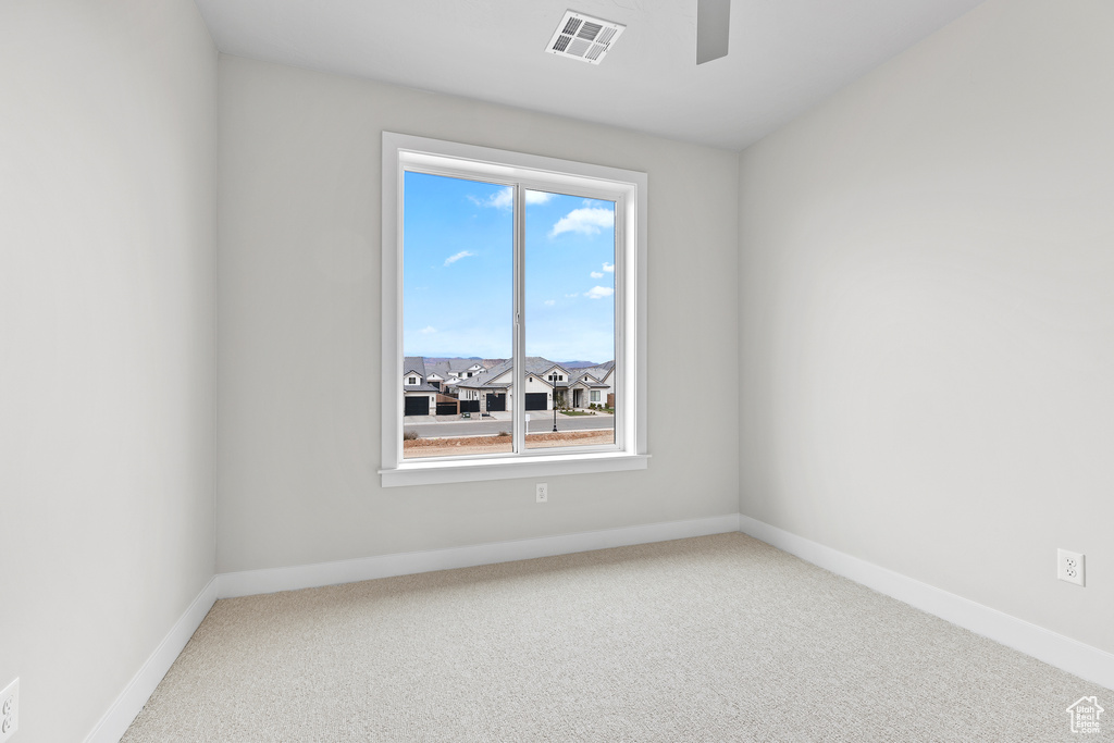 Carpeted spare room with visible vents, ceiling fan, and baseboards