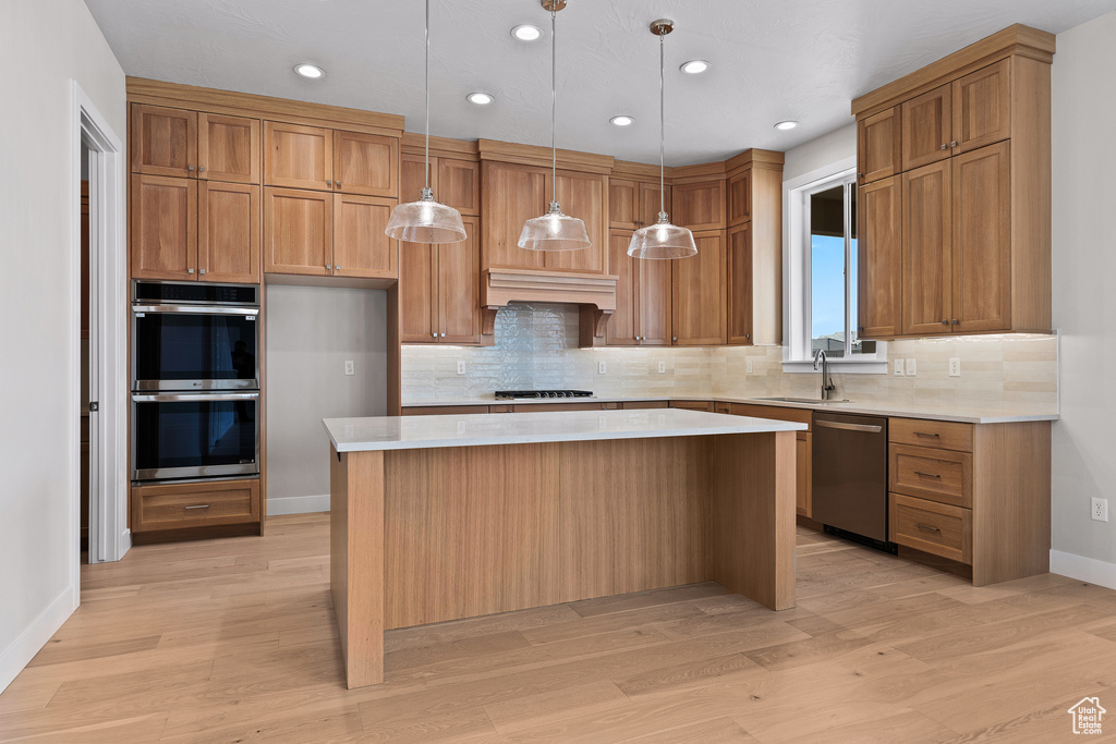 Kitchen with a center island, light countertops, custom range hood, appliances with stainless steel finishes, and a sink