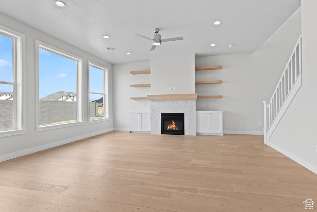 Unfurnished living room featuring baseboards, visible vents, light wood finished floors, and a premium fireplace