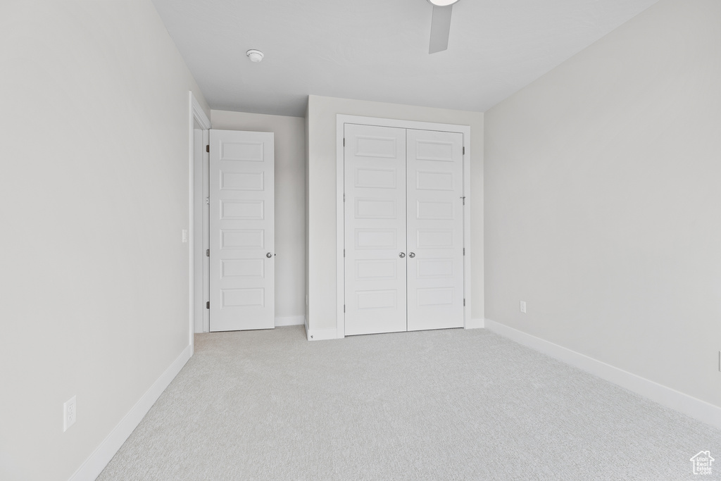 Unfurnished bedroom with ceiling fan, a closet, carpet, and baseboards