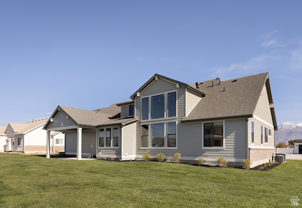 Back of property featuring central AC, a lawn, and a patio area