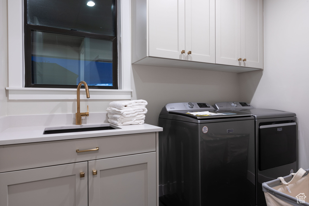 Laundry area featuring cabinets, separate washer and dryer, and sink