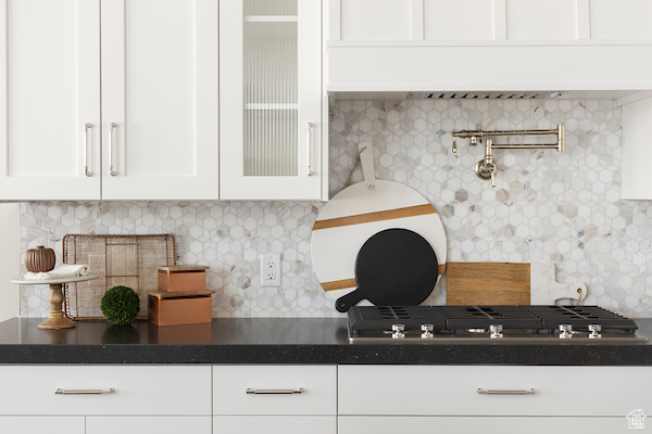 Kitchen with stainless steel gas cooktop, white cabinetry, and decorative backsplash