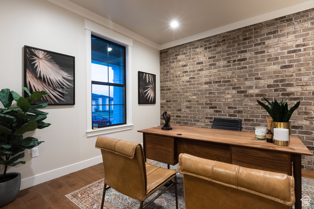 Office space featuring dark wood-type flooring and brick wall