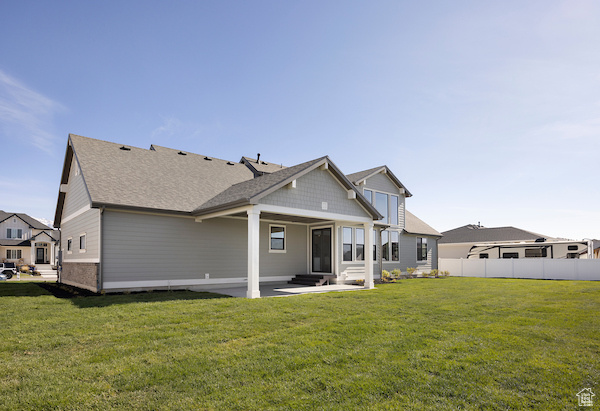 Back of house with a patio area and a lawn