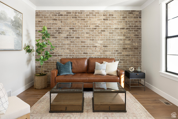 Interior space with hardwood / wood-style floors, ornamental molding, and brick wall