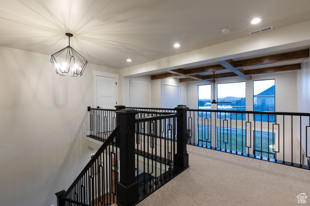 Hallway with beamed ceiling, a chandelier, coffered ceiling, and carpet flooring