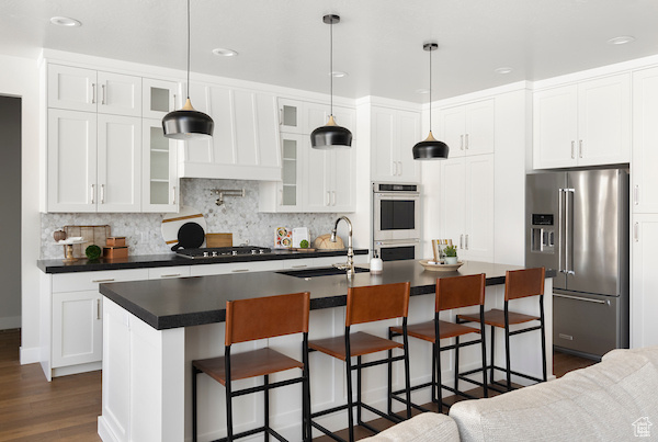 Kitchen with appliances with stainless steel finishes, a breakfast bar, sink, and a center island with sink