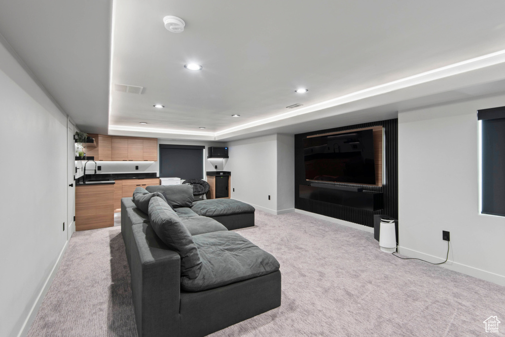 Carpeted living room with a tray ceiling and sink