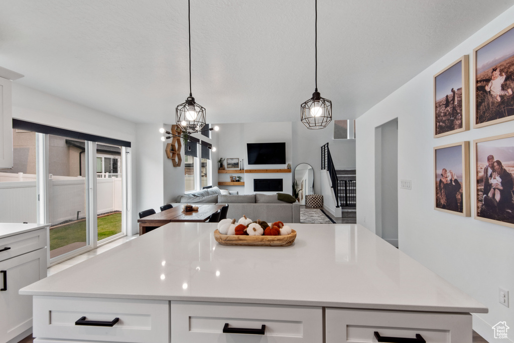 Kitchen with an inviting chandelier, a center island, white cabinets, and hanging light fixtures