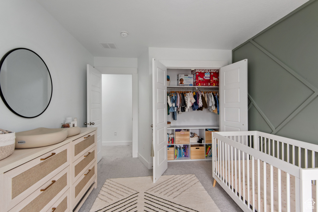 Carpeted bedroom with a closet and a crib