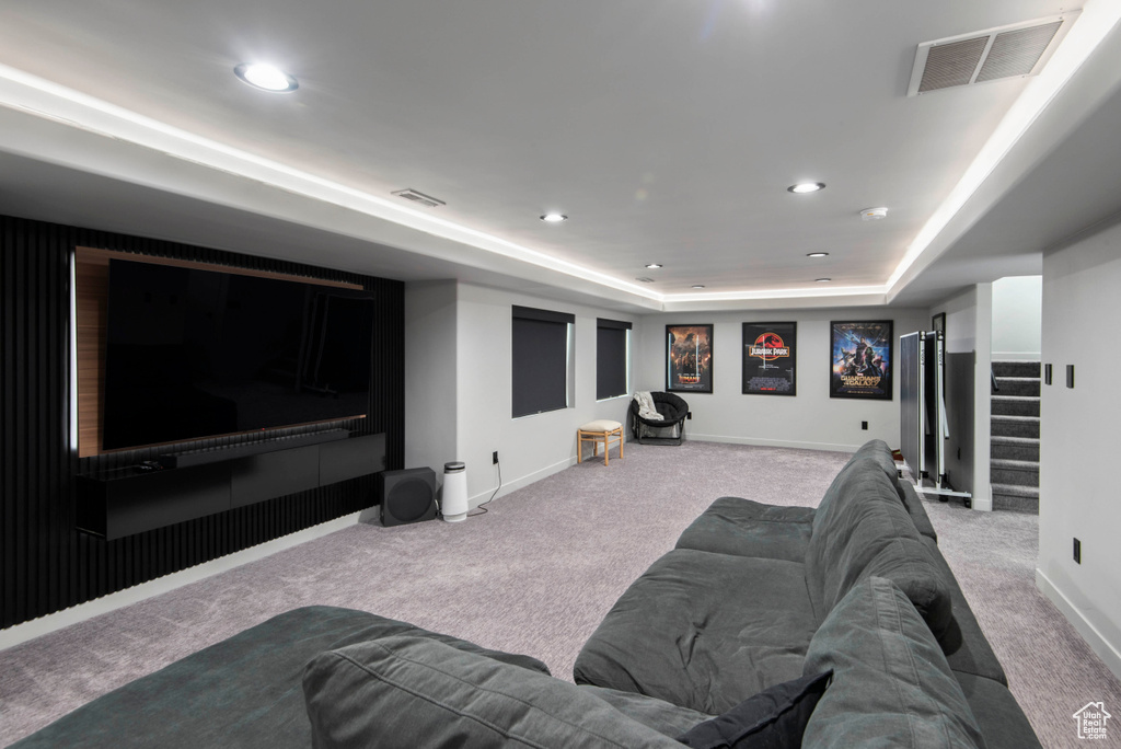 Home theater room with a raised ceiling and light colored carpet