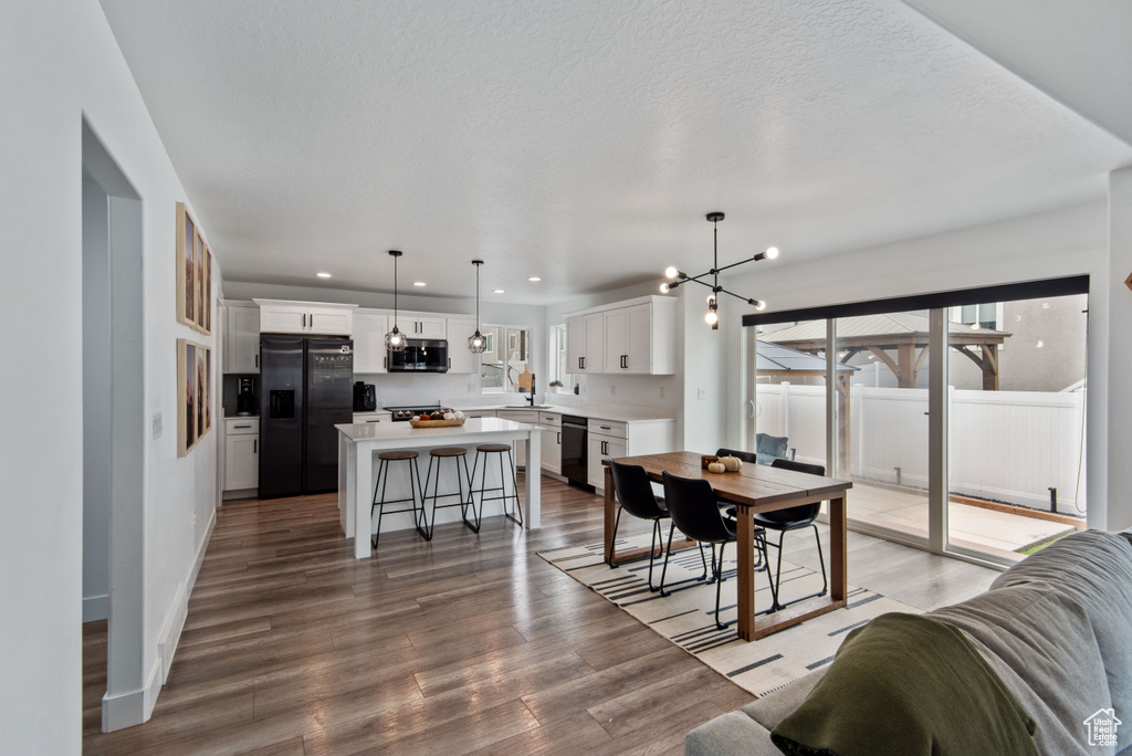 Dining area featuring light wood-type flooring, a notable chandelier, and a textured ceiling