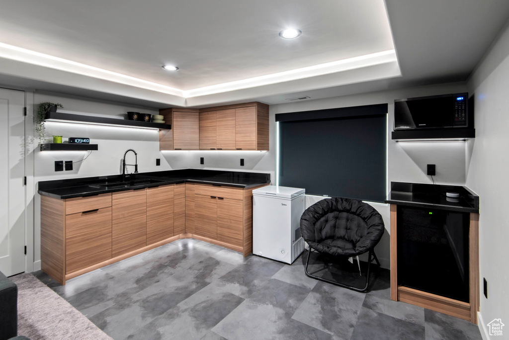 Kitchen with a raised ceiling, fridge, and sink