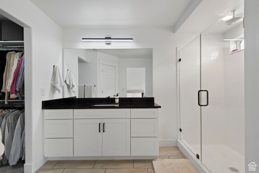 Bathroom with vanity, tile patterned flooring, and a shower with door