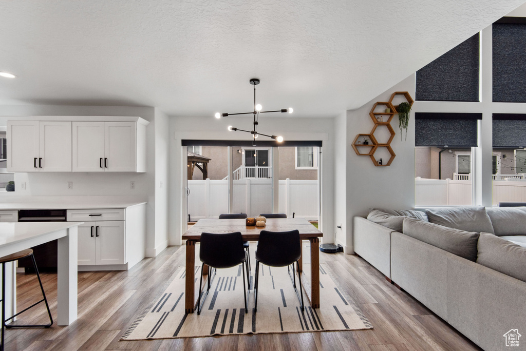 Dining room with light wood-type flooring, a notable chandelier, and a textured ceiling